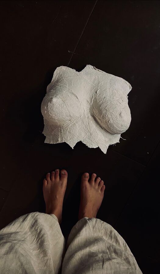 Plaster-bandage torso cast lying on a dark floor