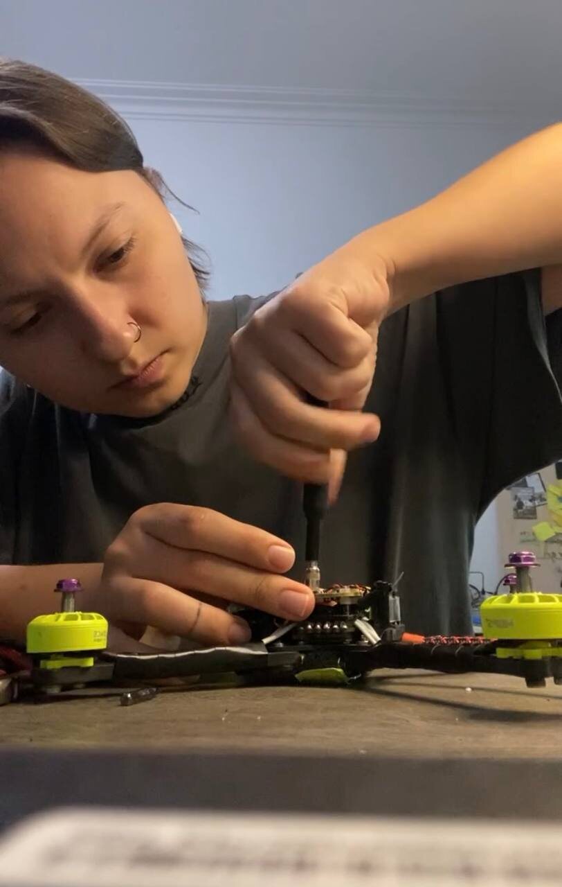 Ancha fastening a motor on an FPV drone at her workbench